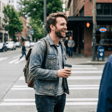 Happy man smiling while walking in city, representing the confidence of healthy skin and nails with Kerassentials