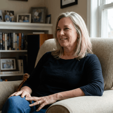 A relaxed, confident woman at home, enjoying the benefits of Kerassentials for healthy skin and nails